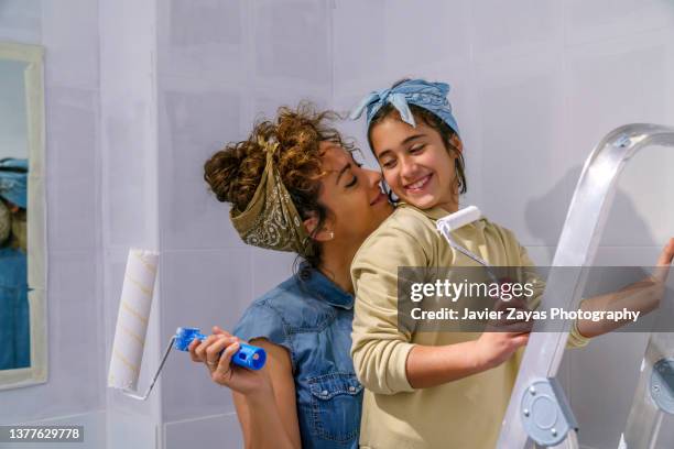 mother and daughter painting a wall of her house together - working class mother stock pictures, royalty-free photos & images