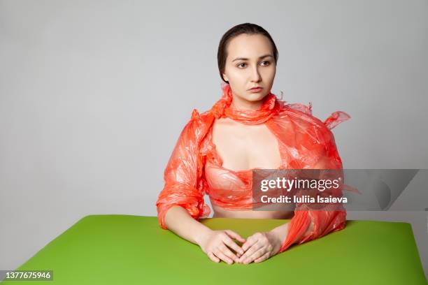 woman in ripped used plastic film at table in studio - regression film - fotografias e filmes do acervo