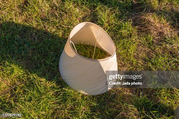 broken lamp shade lying on a lawn in the sun - lamp shade stockfoto's en -beelden