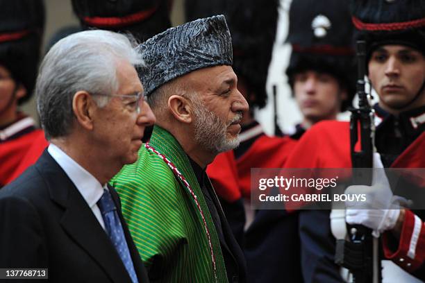 Italian Prime Minister Mario Monti and Afghanistan's President Hamid Karzai review an honour guard prior their meeting on January 26, 2012 at Palazzo...