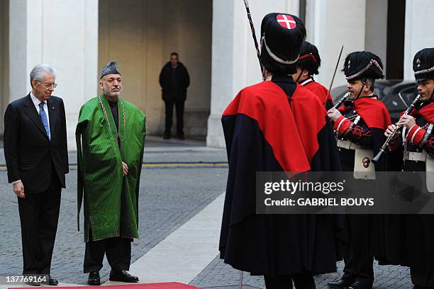 Italian Prime Minister Mario Monti and Afghanistan's President Hamid Karzai review an honour guard prior their meeting on January 26, 2012 at Palazzo...