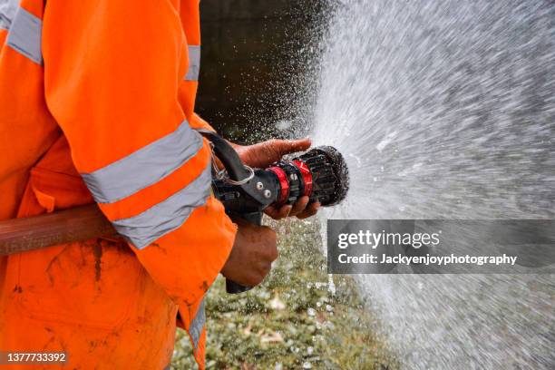 firefighter using extinguisher - feuerwehrauto stock-fotos und bilder