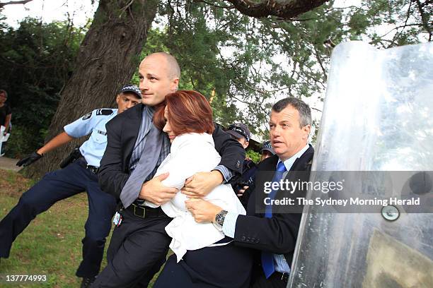 Australian Prime Minister Julia Gillard is escorted by police to a waiting car during a heated Aboriginal protest at an Australia Day awards ceremony...