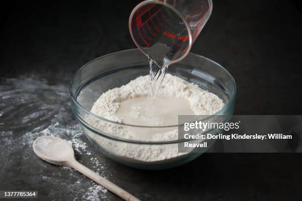 making bread, step 1: pouring tepid water into a well in the centre of the dry ingredients - water in measuring cup stock pictures, royalty-free photos & images