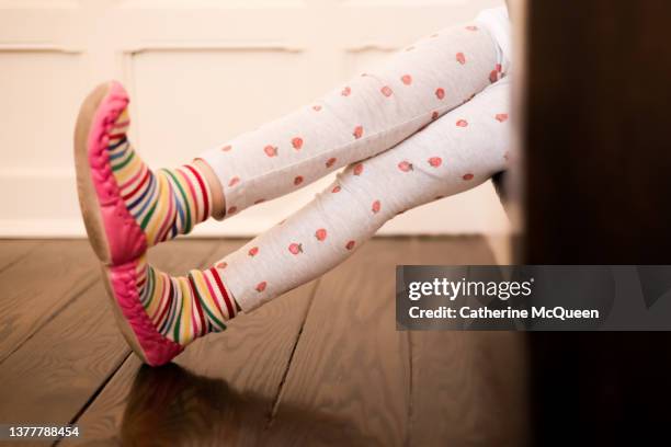 side profile view of young girl’s legs outstretched while sitting on steps wearing vibrant colored moccasins & leggings - girls in leggings stock-fotos und bilder