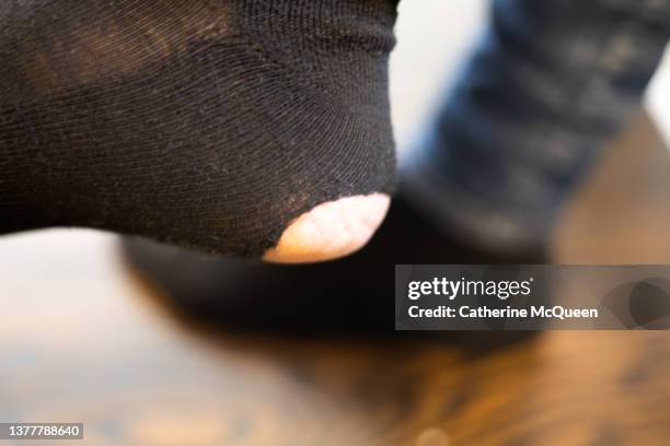 woman noticing sock with large hole in heel - frugality stock pictures, royalty-free photos & images