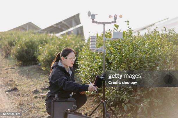 agricultural scientists record weather data at solar power station - meteorologe stock-fotos und bilder