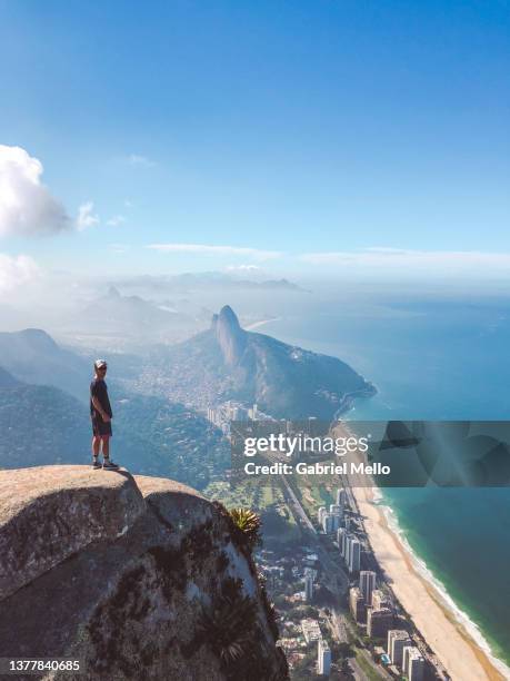 man standing on top of pedra da gavea rio de janeiro - sao conrado beach stock pictures, royalty-free photos & images