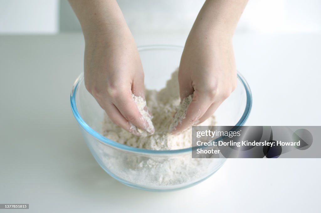 Hands rubbing butter into flour in bowl