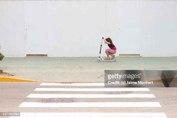 child crouched on his scooter - zebra crossing 個照片及圖片檔