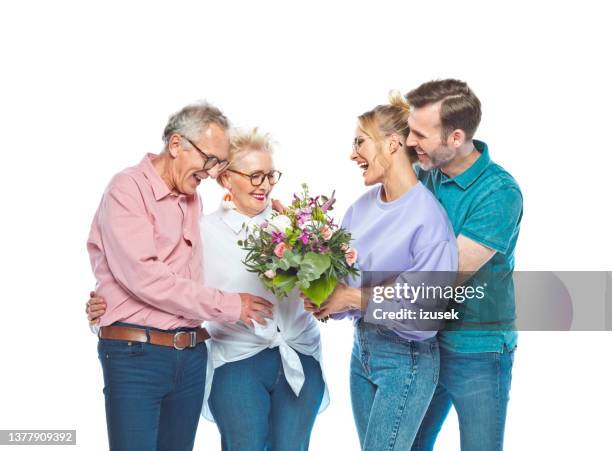 cheerful man and woman giving bouquet to parents - father in law stock pictures, royalty-free photos & images