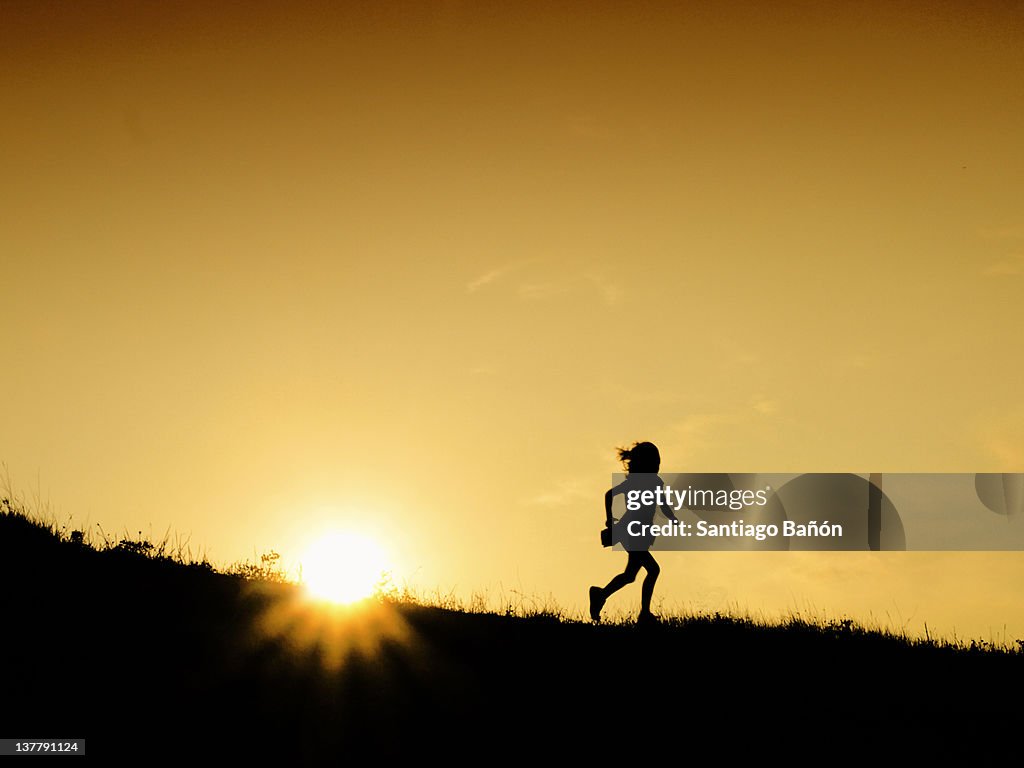 Girl running on hill at sunset