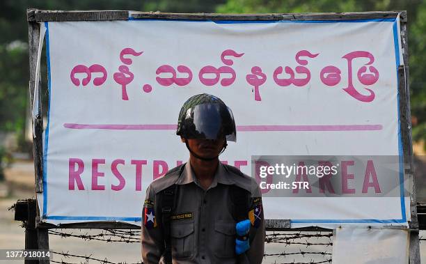 Policeman stands near a check-point set up across the road leading to Myanmar's opposition leader Aung San Suu Kyi's house in Yangon on November 13,...