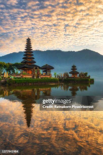 pura ulun danu hindu temple on lake beratan, bali, in the early morning surrounding mountains , creating an aura of spiritual mystery. - bratansee stock-fotos und bilder