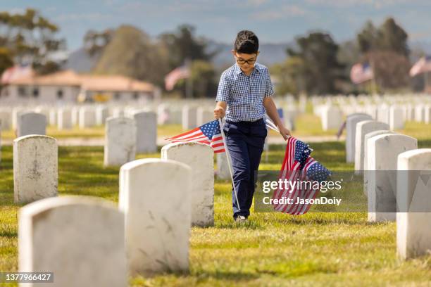 young boy placing flags on veterans grave - world war i peace stockfoto's en -beelden