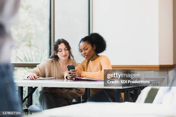 teen girls look at smart phone while unrecognizable teacher lectures - real life science stock pictures, royalty-free photos & images