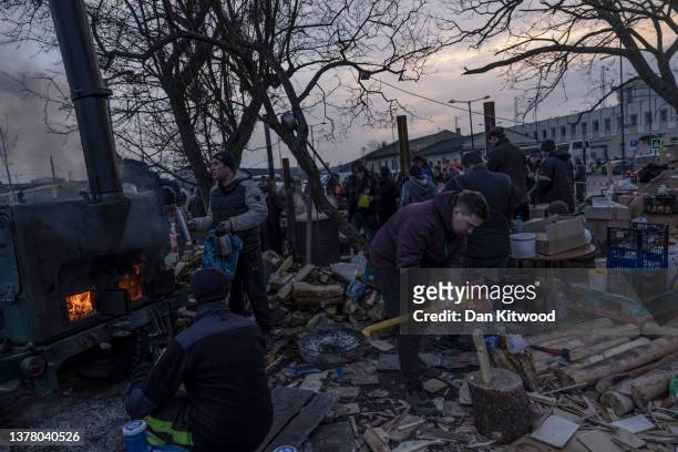 Man chops wood as volunteers help provide hot water and food at the central train station on March 03, 2022 in Lviv, Ukraine. More than a million...