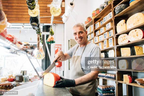 cheesemonger serving customer orders - deli counter stockfoto's en -beelden