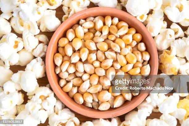 popcorn and popcorn kernels side by side - corn kernel stock-fotos und bilder