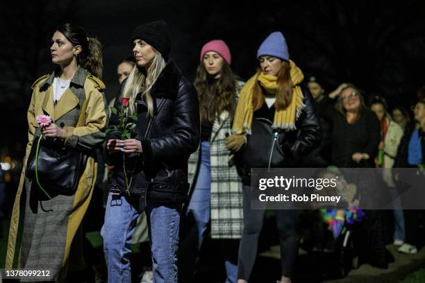 People walk through Clapham Common carrying flowers towards the bandstand as part of an organised walk in memory of Sarah Everard on March 03, 2022...