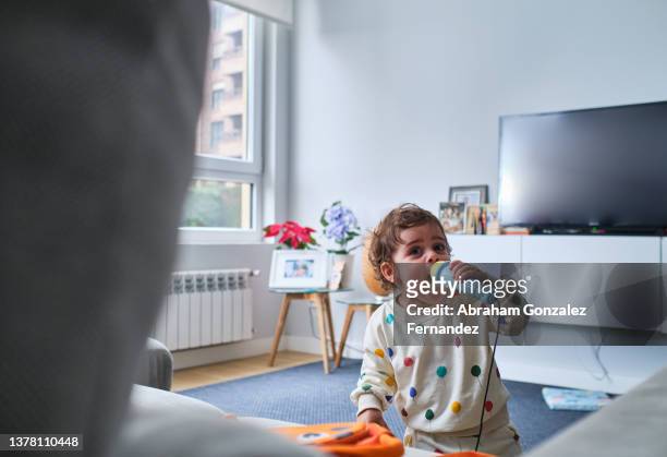 funny little girl playing and singing with toy microphone - baby attitude stock pictures, royalty-free photos & images