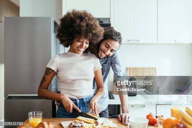 multiracial family in kitchen expressing love and happiness - happy couple kitchen stock pictures, royalty-free photos & images