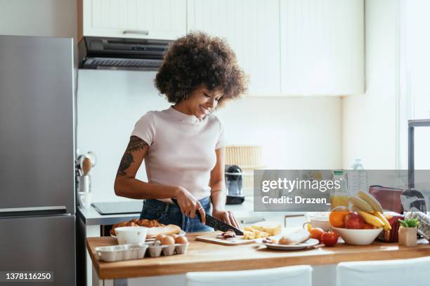 mixed race woman cooking healthy food at home - göra en macka bildbanksfoton och bilder