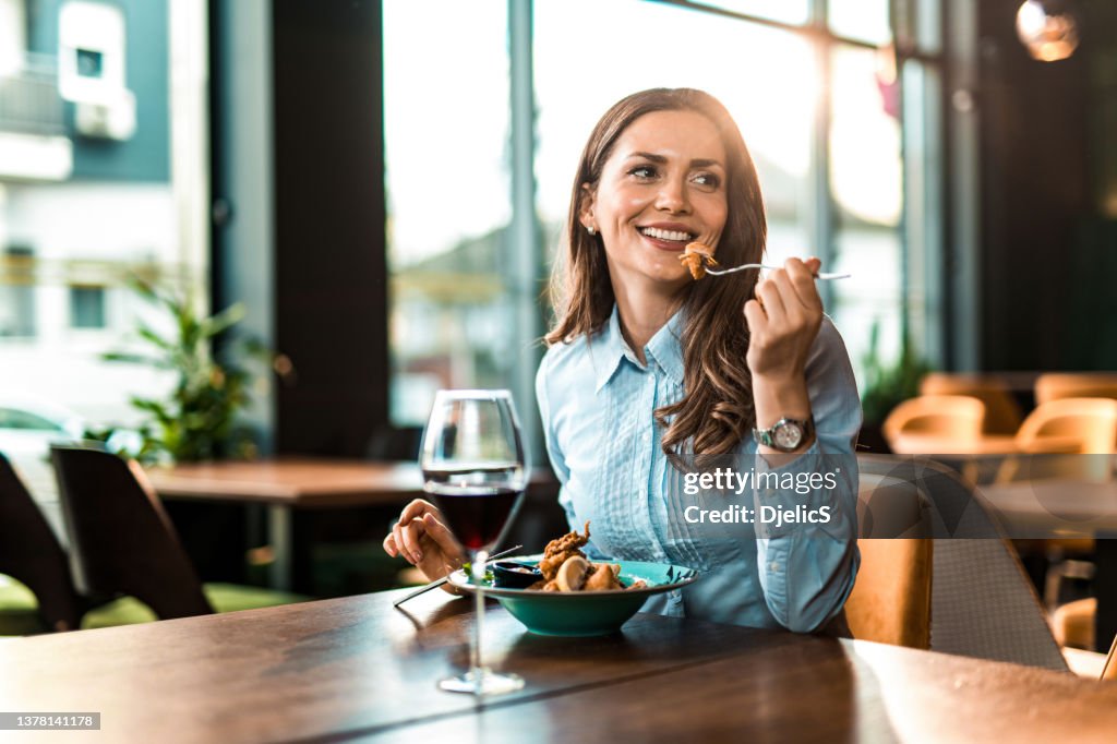 Happy woman having lunch and wine in a restaurant.