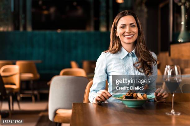 happy woman having lunch and wine in a restaurant. - woman in a restorant stock pictures, royalty-free photos & images