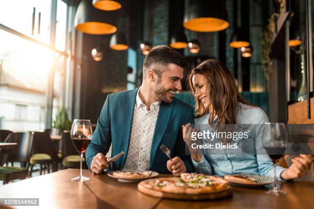 beautiful couple eating pizza together in a restaurant. - alleen volwassenen stockfoto's en -beelden