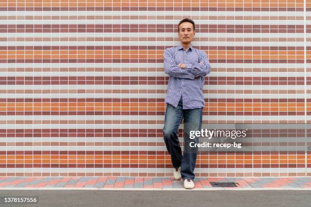 portrait of japanese mature man - person standing infront of wall stockfoto's en -beelden