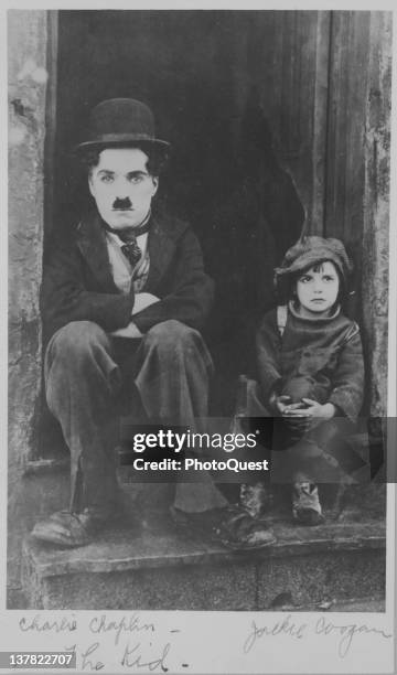 Publicity still of British actor Charlie Chaplin and American child actor Jackie Coogan as they sit in a doorway in the film 'The Kid' , California,...