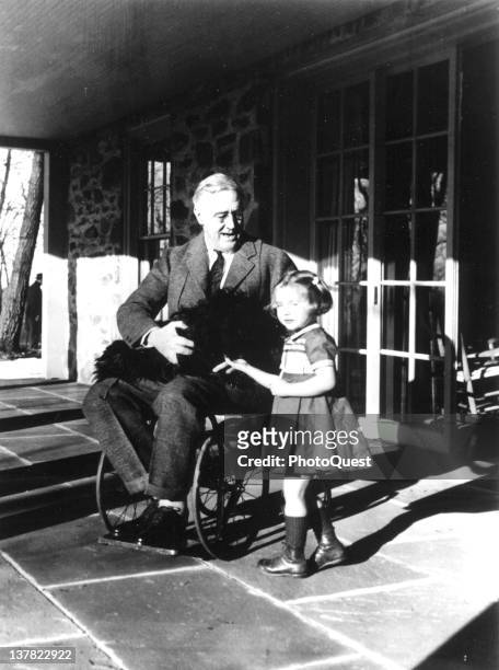 American President Franklin D. Roosevelt poses with his dog Fala and a young girl named Ruthie Bie on the porch at Top Cottage, Hyde Park, New York,...