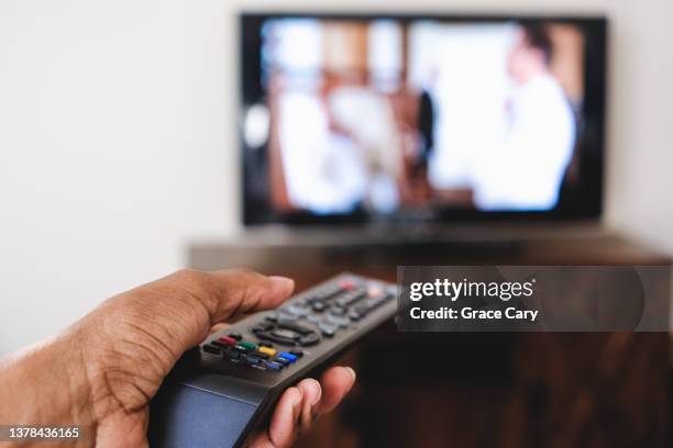 woman points remote control at tv - alter tv stock pictures, royalty-free photos & images