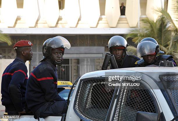 Riot policemen sit on the back of a pickup truck as they patrol the street giving way to the headquarters of the Criminal Investigation Unit in...