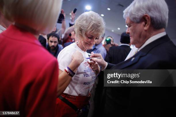 Supporter of Republican presidential candidate, former Speaker of the House Newt Gingrich has him sign her t-shirt as his wife Callista Gingrich...