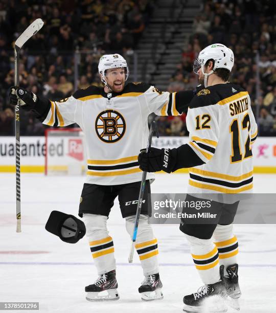 Hat thrown by a fan lands on the ice as Matt Grzelcyk and Craig Smith of the Boston Bruins celebrate Smith's third-period goal, his third goal of the...