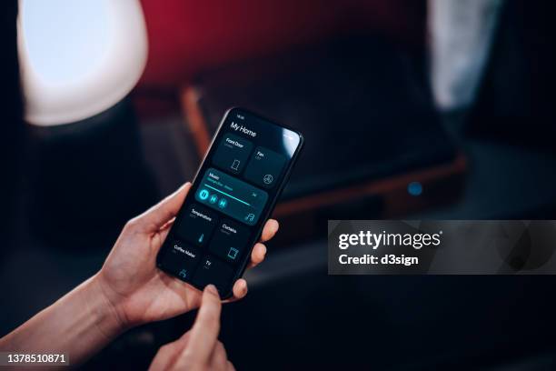 cropped shot of woman's hand using smartphone and setting up the intelligent home system, remote-controlling and playing music on smart speaker of her modern smart home. smart living. lifestyle and technology. smart home technology concept - electrical panel box stock-fotos und bilder