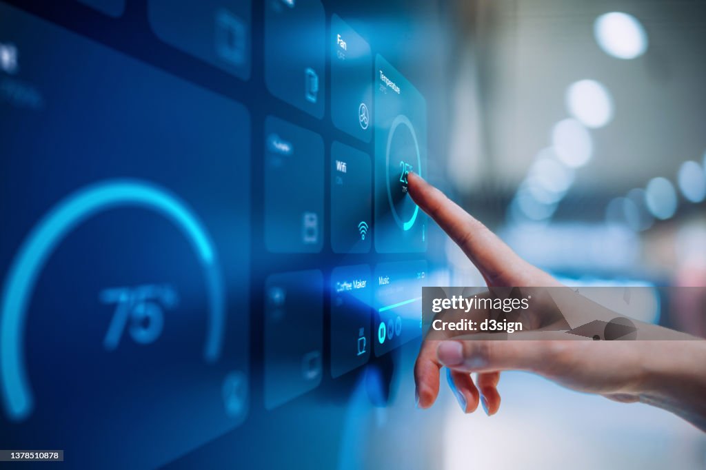 Close up of woman's hand setting up intelligent home system, controlling smart home appliances with control panel of a smart home. Home automated system controlled from a dashboard. Smart living. Lifestyle and technology. Smart home technology concept