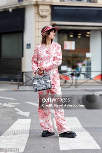 Influencer Lea Naumann wearing a red and white Toile de Jouy Silk Twill Chez Moi shirt and matching pants by Dior, a red D-Oblique visor hat by Dior,...
