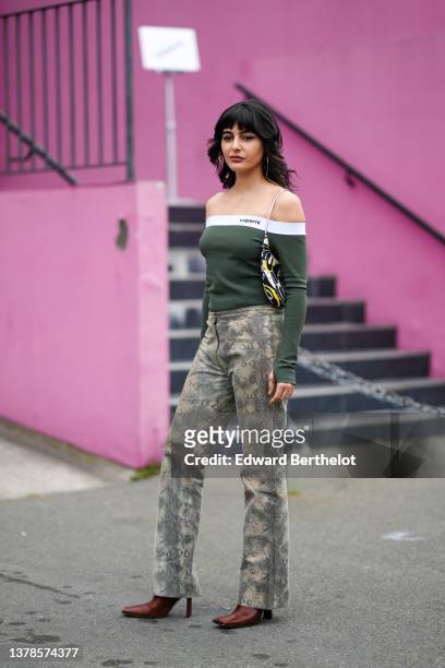 Maria Bernad wears gold earrings, a khaki with white borders shoulder-off / long sleeves t-shirt from Coperni, a black / yellow / white / beige print...