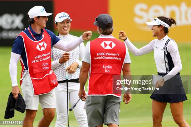 Amy Yang of South Korea and Lydia Ko of New Zealand bump fists with their caddies on the 18th green after finishing the second round of the HSBC...