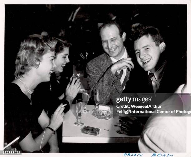 American actor Orson Bean shares a laugh and a drink with unidentified others, mid twentieth century. Note that the image was developed backwards,...