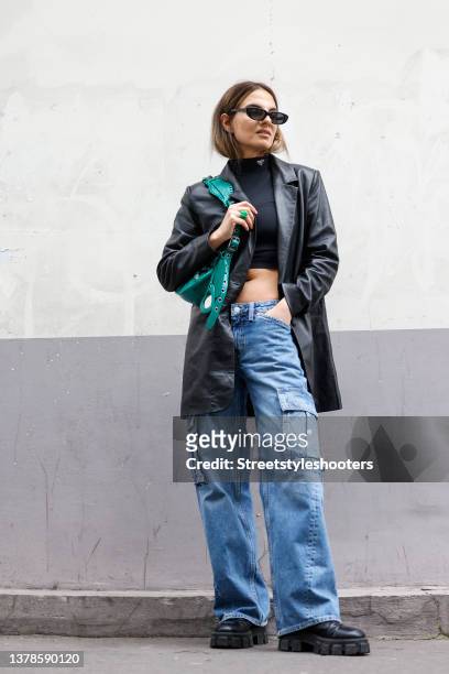 Influencer Anna Winter wearing a black cropped turtleneck top by Prada, a black leather blazer by Mango, blue wide leg cargo denim jeans pants by...