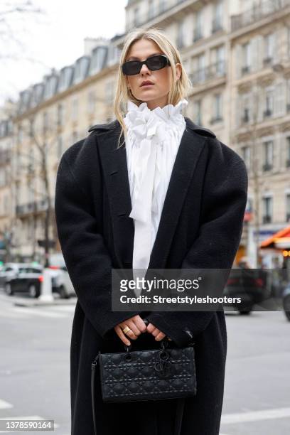 Influencer Alessa Winter wearing a white mini dress by Patou, a white bluse with bow and ruffles by Patou, a long black coat by The Frankie Shop, a...