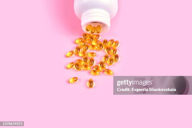fish oil supplements in a white bowl on pink background. - vitamin d stock pictures, royalty-free photos & images
