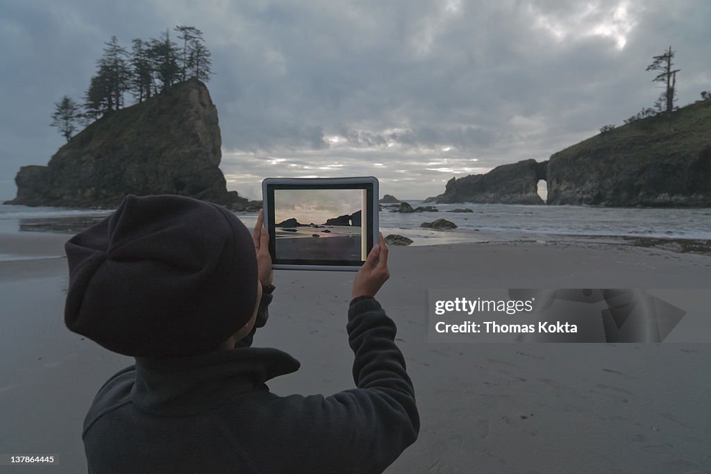 Person with tablet computer on the coast