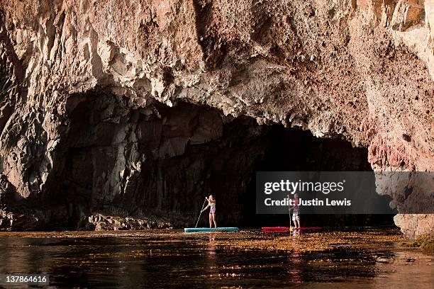 two stand up paddle boarders emerging from cave - insel catalina island stock-fotos und bilder