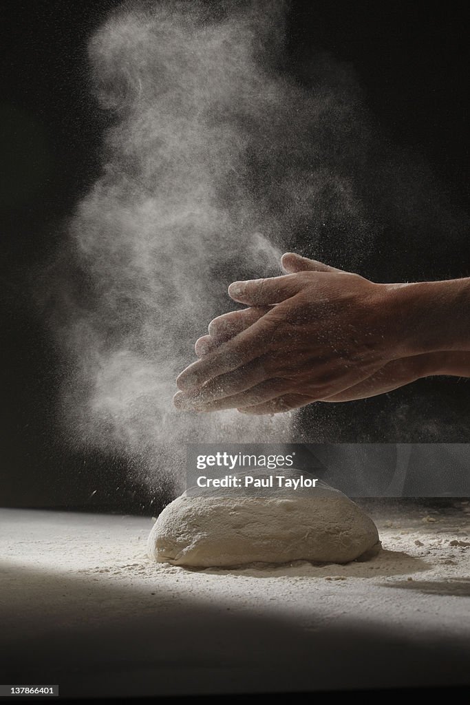 Hands and Cloud of Flour Over Dough