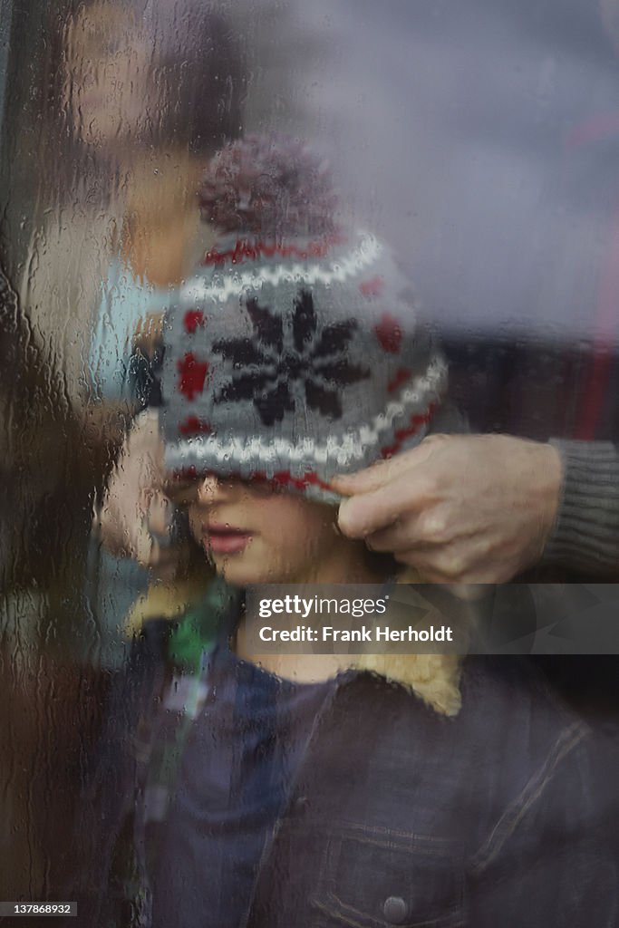 Father pulling own hat over sons eyes